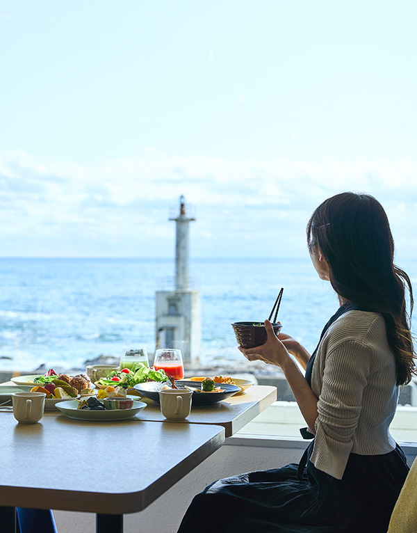 海を眺めながら朝食ビュッフェを楽しむ女性のイメージ